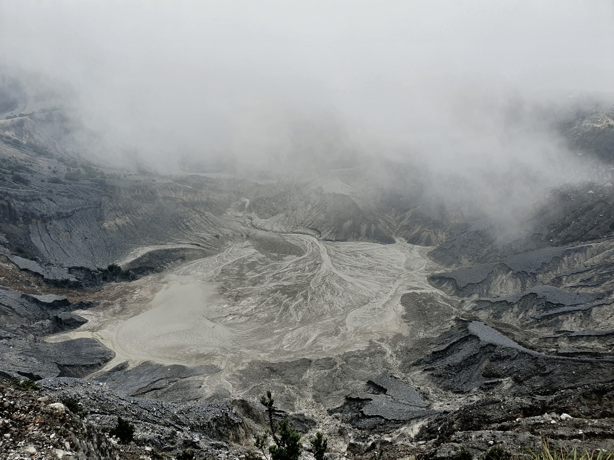 Rough volcanic crater with foamy hot water in mist